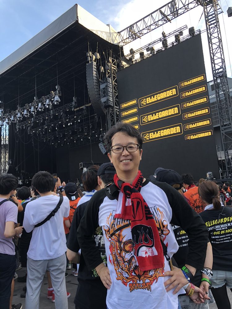 ELLEGARDEN復活ライブの会場でステージを背に立つ目加田